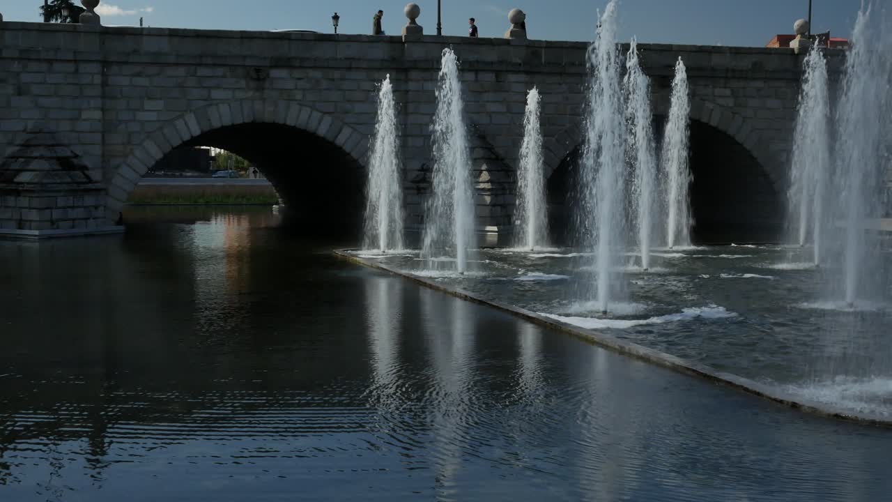 fuente de chorros de agua en la ciudad cerca de un puente de piedra