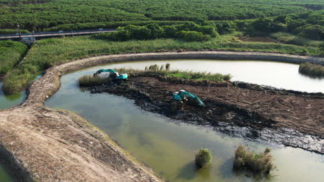 two excavators restoring wetlands at guandu nature park, taipei, aerial shot