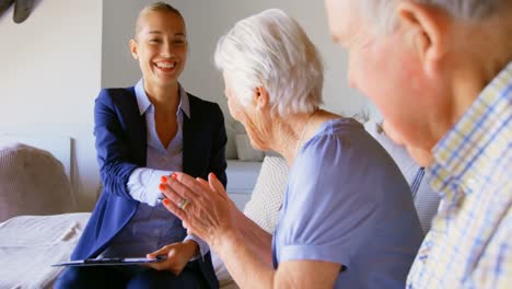 Caucasian-female-real-estate-agent-shaking-hands-with-senior-couple-at-home-4k