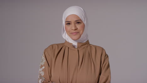 studio portrait of smiling muslim woman wearing hijab against plain background 1