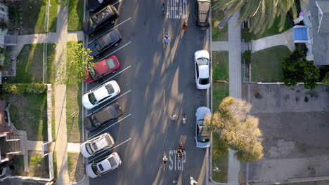 aerial top-down view of a residential street with cyclists and parked cars