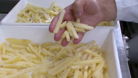 hand takes a sample of fries to check