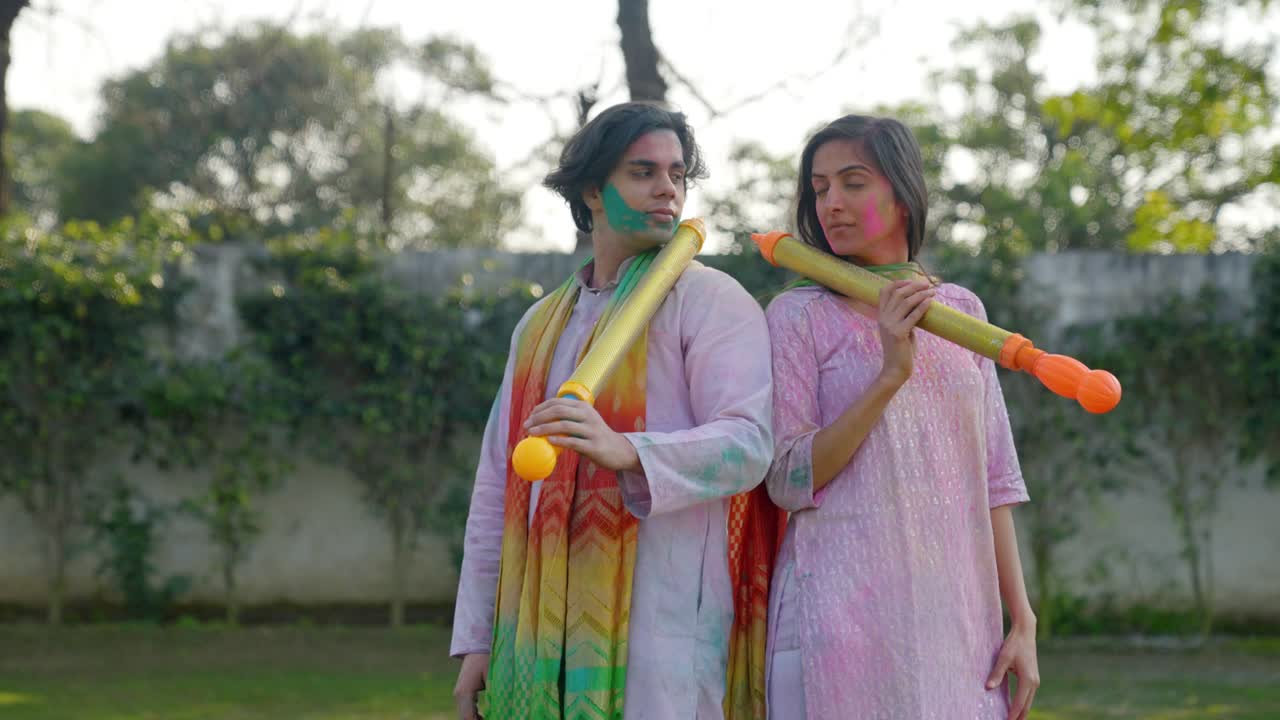 Indisk par poserer med vandpistol til en Holi-festival.