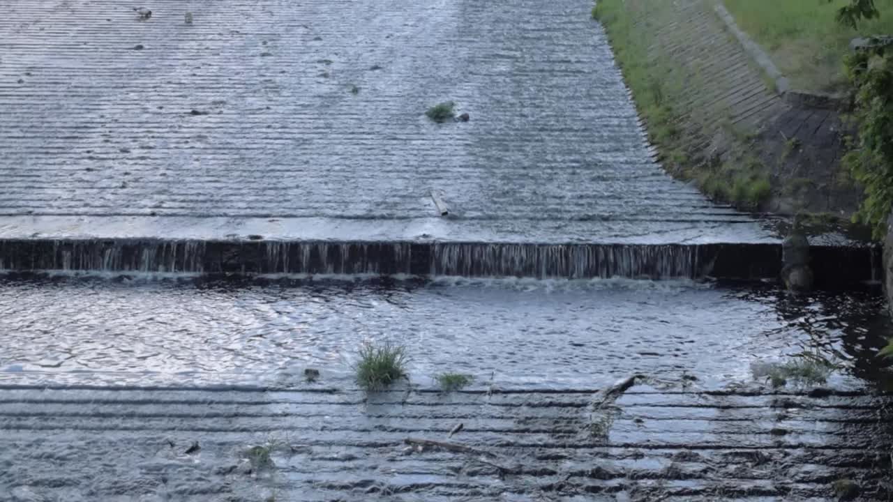 Weir at reservoir gushing water wide tilting shot