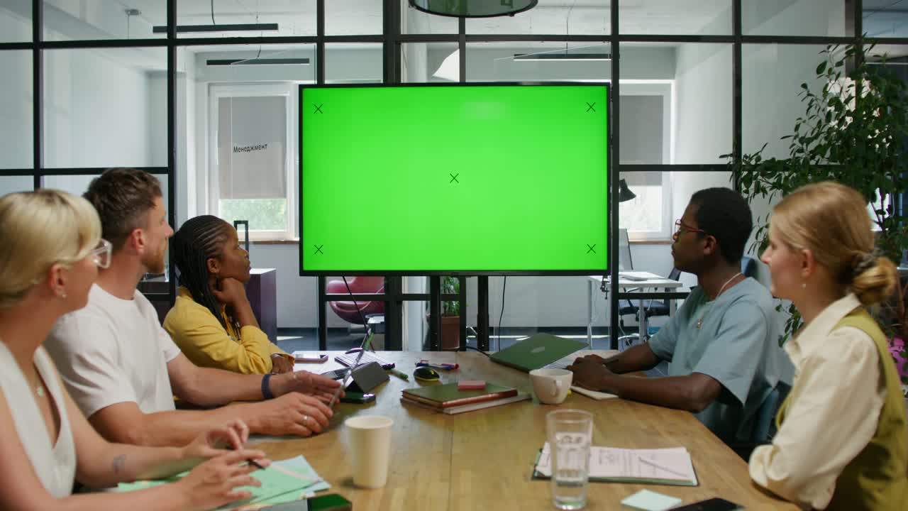 Riunione di lavoro attorno a una TV con schermo verde