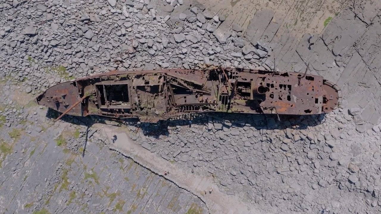 Il relitto arrugginito della Plassey giace incagliato su una costa rocciosa delle Isole Aran, mentre un drone sorvola direttamente dall'alto in pieno giorno.