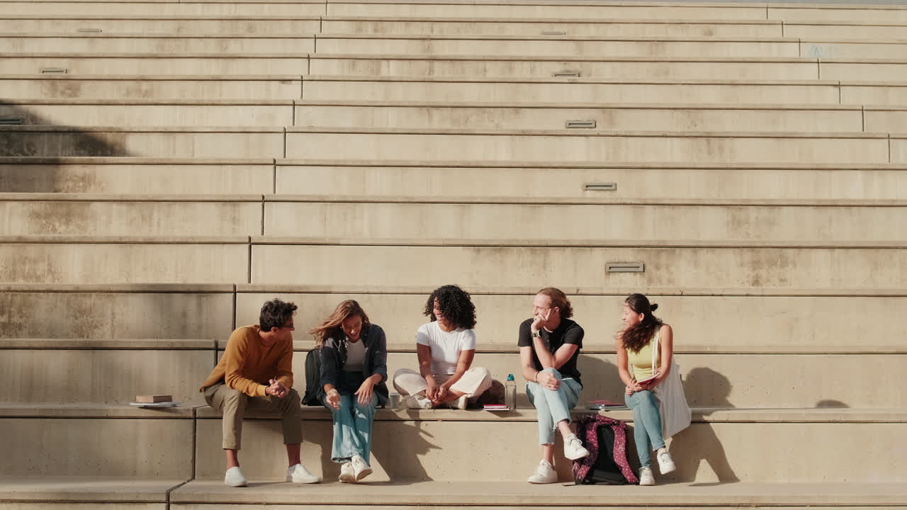 The group of happy students with study items is sitting with university building
