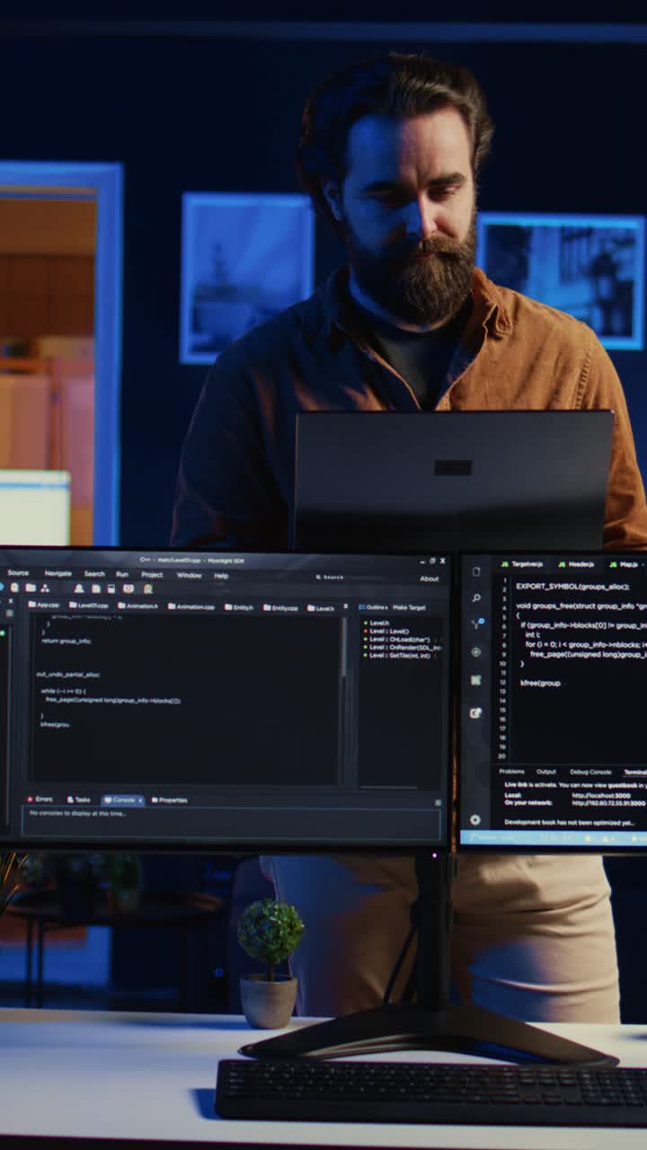 Bearded Man Working on Laptop and Multiple Screens at Night