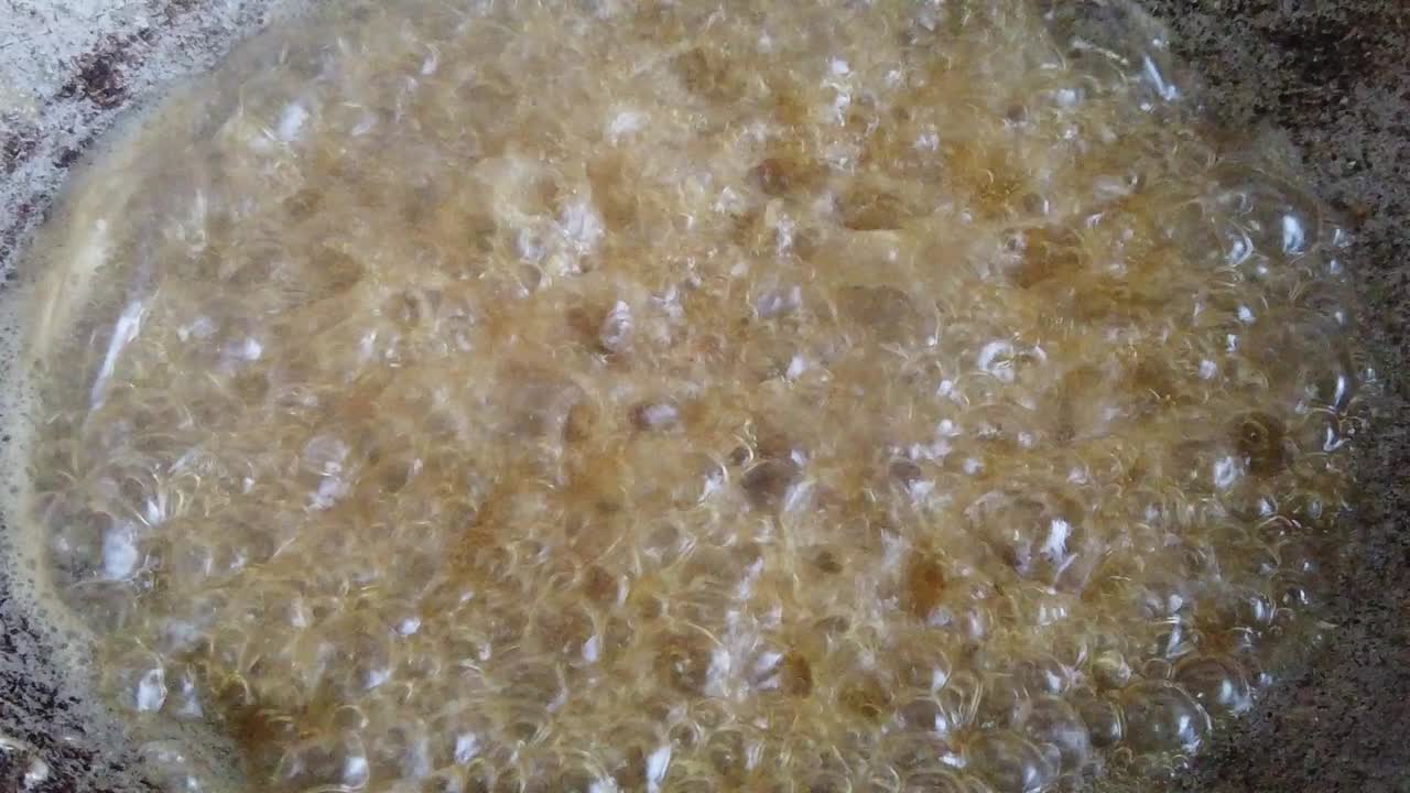 a slow motion of frying anchovies in the hot palm oil and metal pan