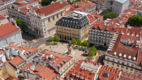 Aerial-orbit-of-a-monument-and-yellow-tram-driving-around-the-city-square-surrounded-by-traditional-colorful-houses-in-Lisbon-city-center