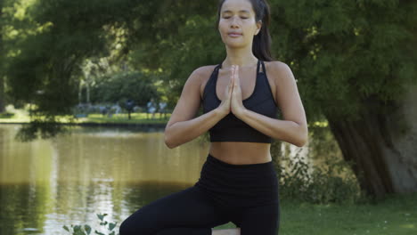 mujer joven haciendo ejercicio de yoga pose de árbol en un hermoso parque
