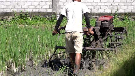 slow motion barefoot man operating rice field tractor