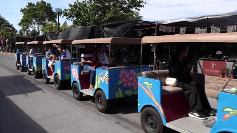 tractor pulling carts with passengers in a market.