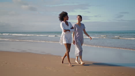 happy women enjoying ocean walk. smiling lesbian couple resting sandy beach