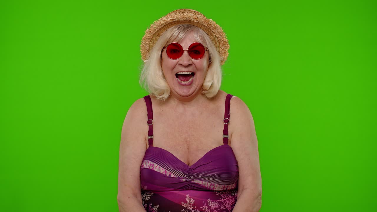 Anziana turista pensionata stupita in costume da bagno, scioccata da una vittoria improvvisa, che esclama "wow" su sfondo chroma key