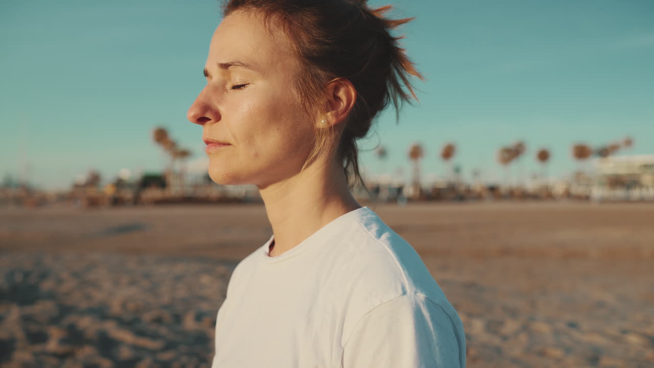 una mujer caucásica meditando en la playa.