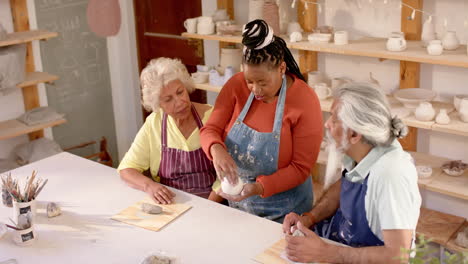 Happy-diverse-group-of-potters-discussing-about-work-in-pottery-studio