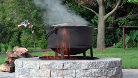 an old fashioned iron kettle over the fire of an outdoor campfire