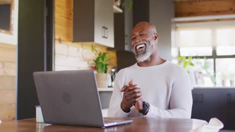 Feliz-Hombre-Afroamericano-Mayor-En-Cabaña-De-Madera,-Usando-Laptop-Para-Videollamadas,-Cámara-Lenta