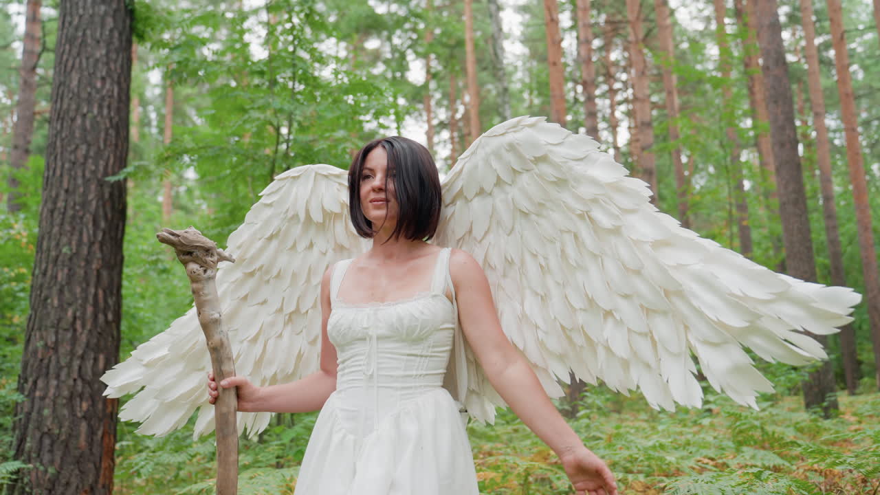 White fairy woman with large angel wings walks gracefully through lush forest, gently touching green plants with admiration, surrounded by sunlight symbolizing magical harmony with nature
