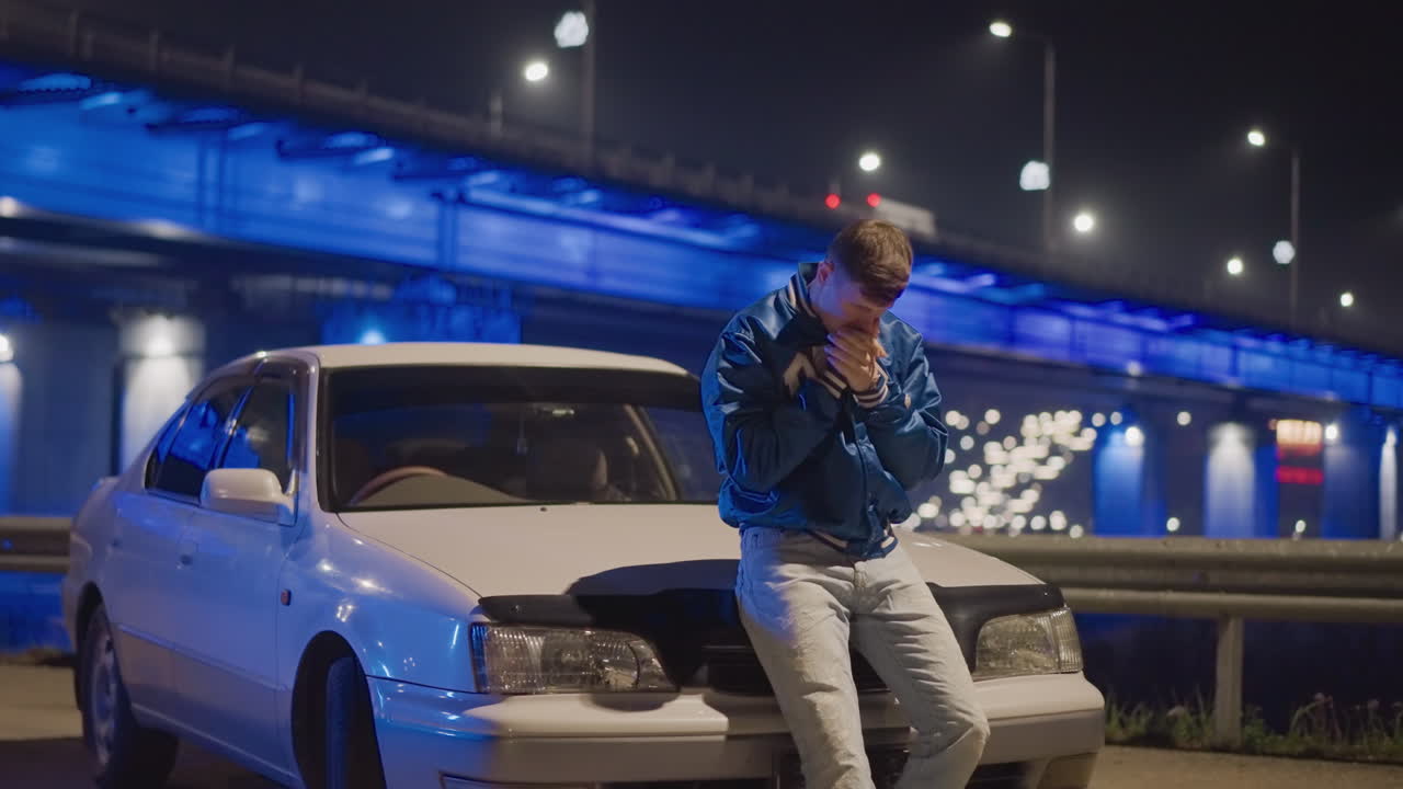 coche nocturno, hombre blanco apoyado en el capó con un puente de neón de fondo, pose enérgica, motor al ralentí, ambiente de crucero, conductor como corredor callejero, conductor como viajero, manos revisando las llaves, movimiento cinematográfico, áspero
