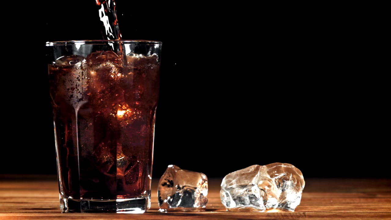 Cola rinfrescante versata in un bicchiere con ghiaccio