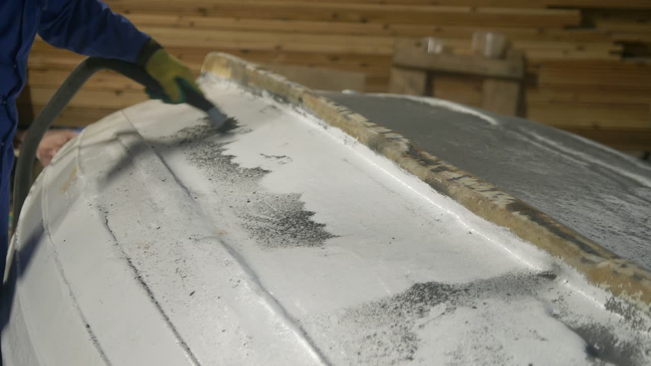 Aspirazione detriti dallo scafo di barche in officina di riparazione