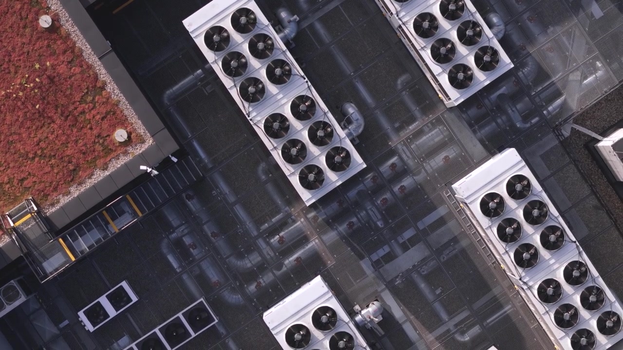 High-angle aerial shot showcasing industrial HVAC cooling units and ventilation infrastructure on a modern data center rooftop, highlighting enterprise thermal management and smart city technology.