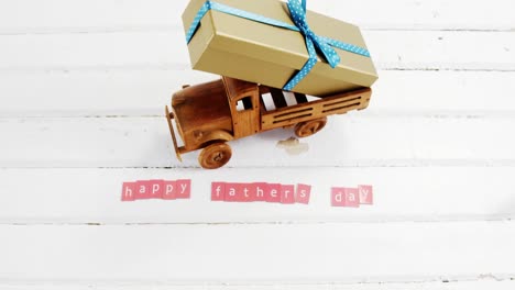 Toy-truck-with-gift-and-happy-fathers-day-blocks-arranged-on-wooden-plank