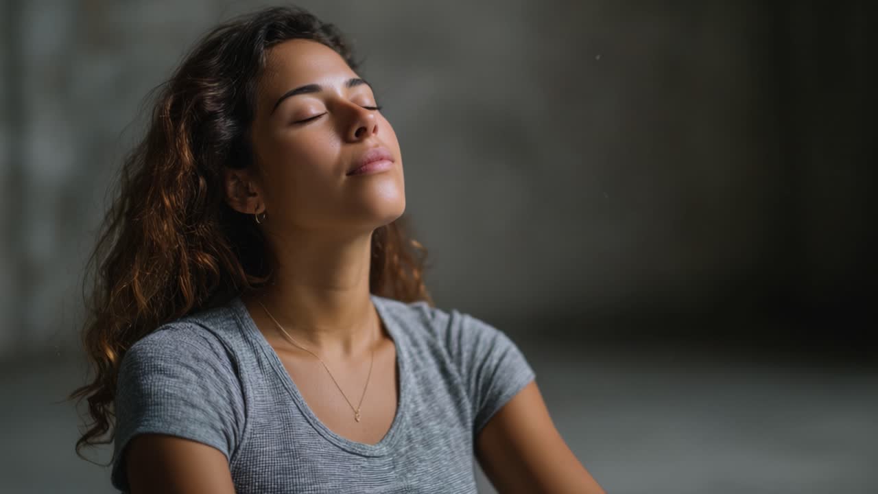Momento di serenità e pace interiore catturato: una giovane donna con gli occhi chiusi abbraccia la tranquillità, riflettendo sulla vita e respirando profondamente in un ambiente calmo.