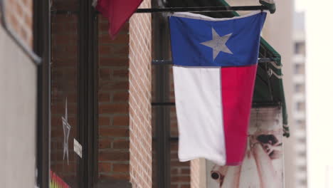 Una-Bandera-Tejana-Colgada-Frente-A-La-Ventana-De-Una-Tienda-En-El-Centro-De-Dallas,-Texas