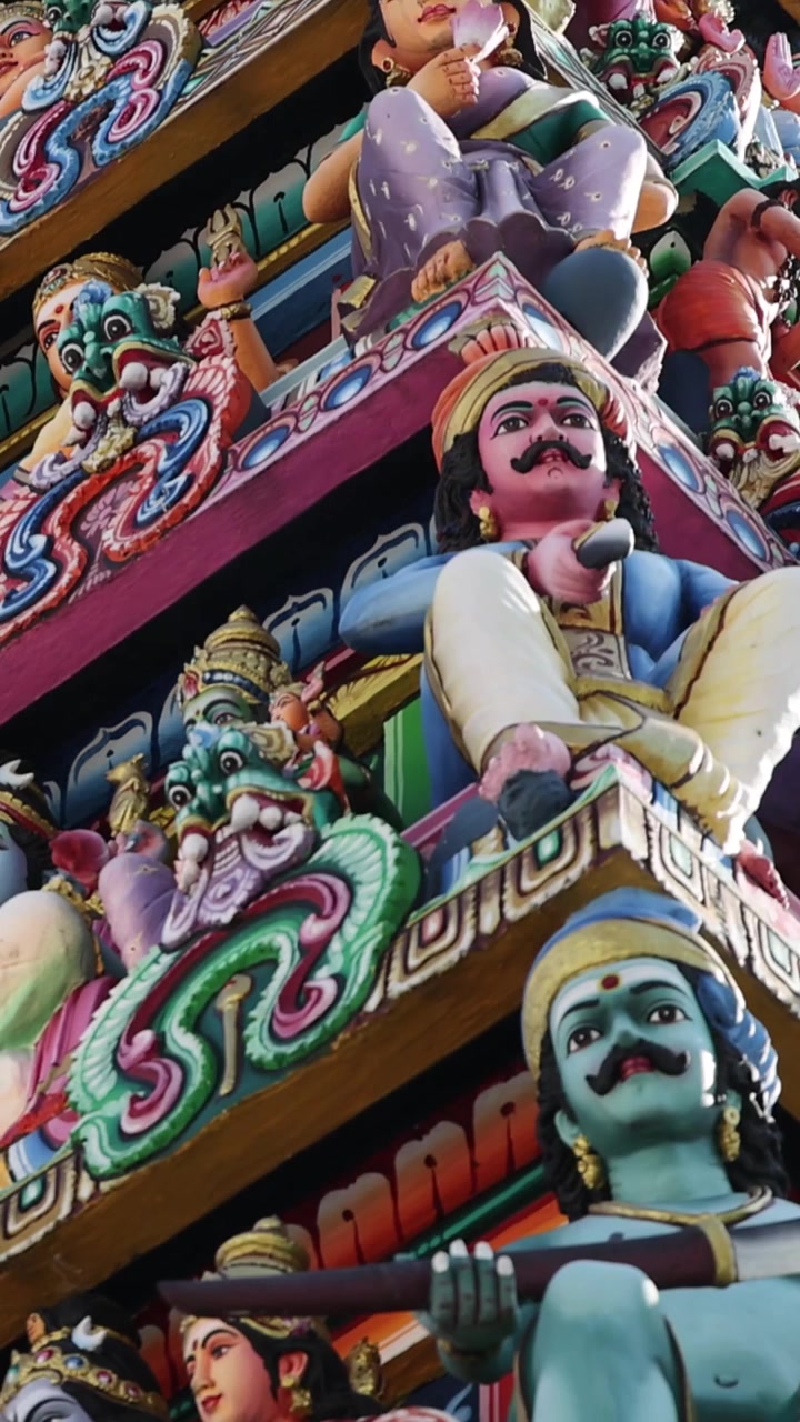 垂直鏡頭傾斜顯示一座寺廟塔門上色彩繽紛的神話雕像和華麗雕刻。