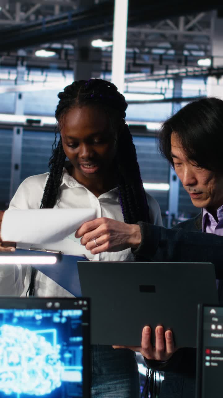 Vertical video Data center engineers managing AI systems, looking over paperwork
