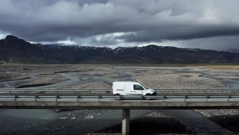 Car-travels-on-scenic-road-in-Iceland-crossing-bridge-over-glacial-melt-water