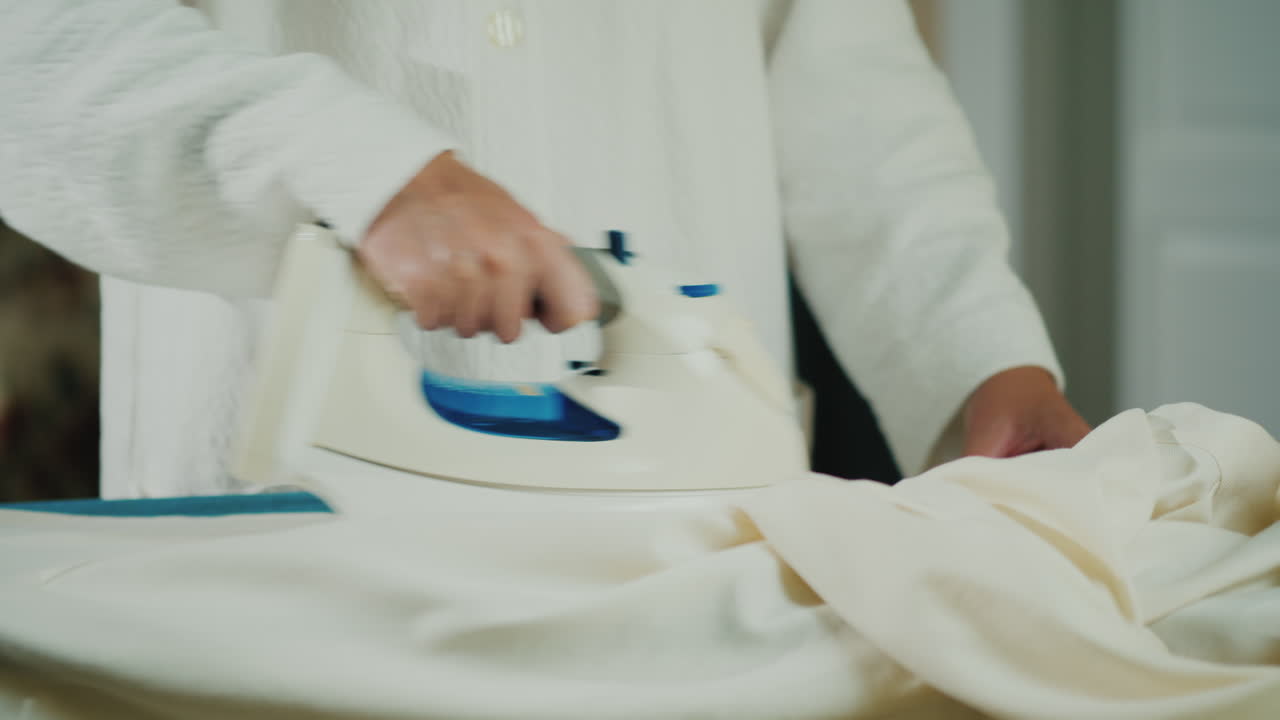 женские руки с утюгом гладят одежду