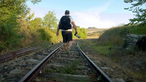 low to the ground shot of a young man walking along deserted train tracks