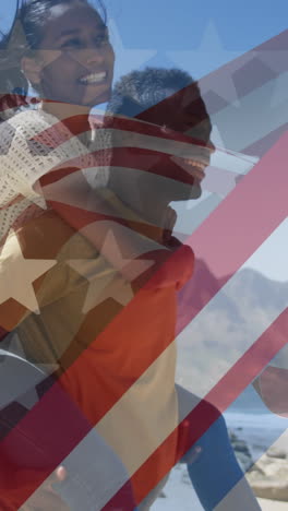 animation of american flag over smiling diverse couple carrying in mountains