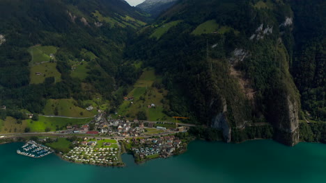 revealing aerial shot of the lakeside village sisikon embedded into hilly and rocky landscape located at the lake lucerne on a sunny summer day.