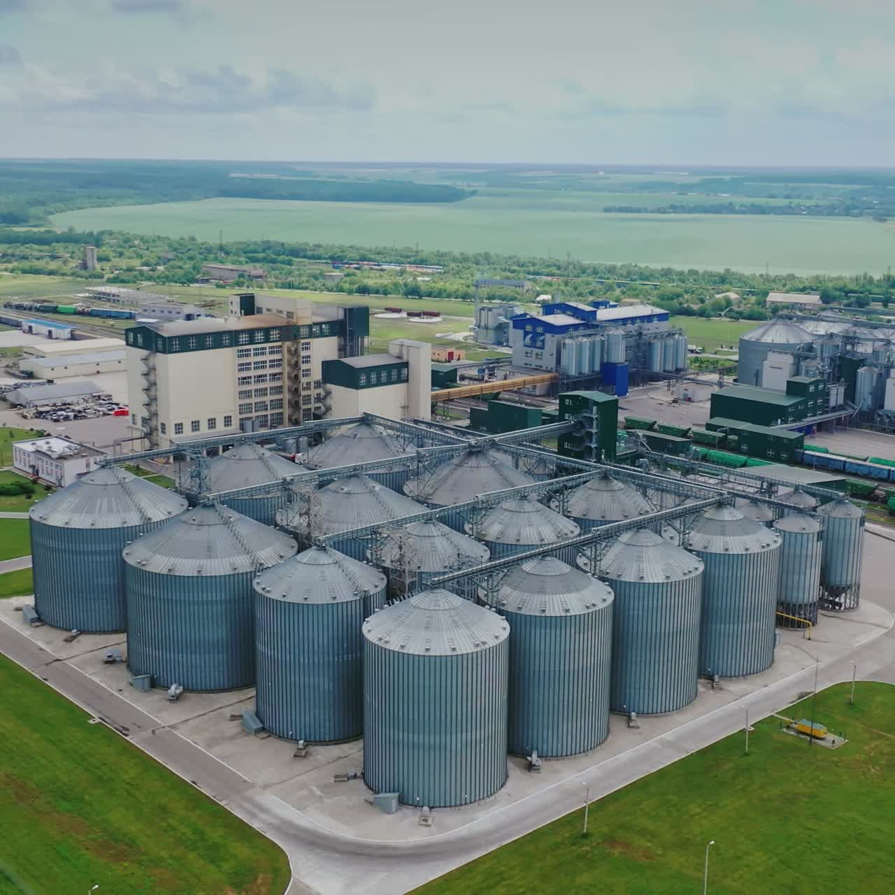 Agribusiness. Elevator for grain storage. Exterior of steel containers on the manufacturing on nature background. Aerial view.
