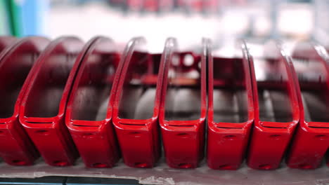 row of metal details in red color after painting. painted billets on shelf