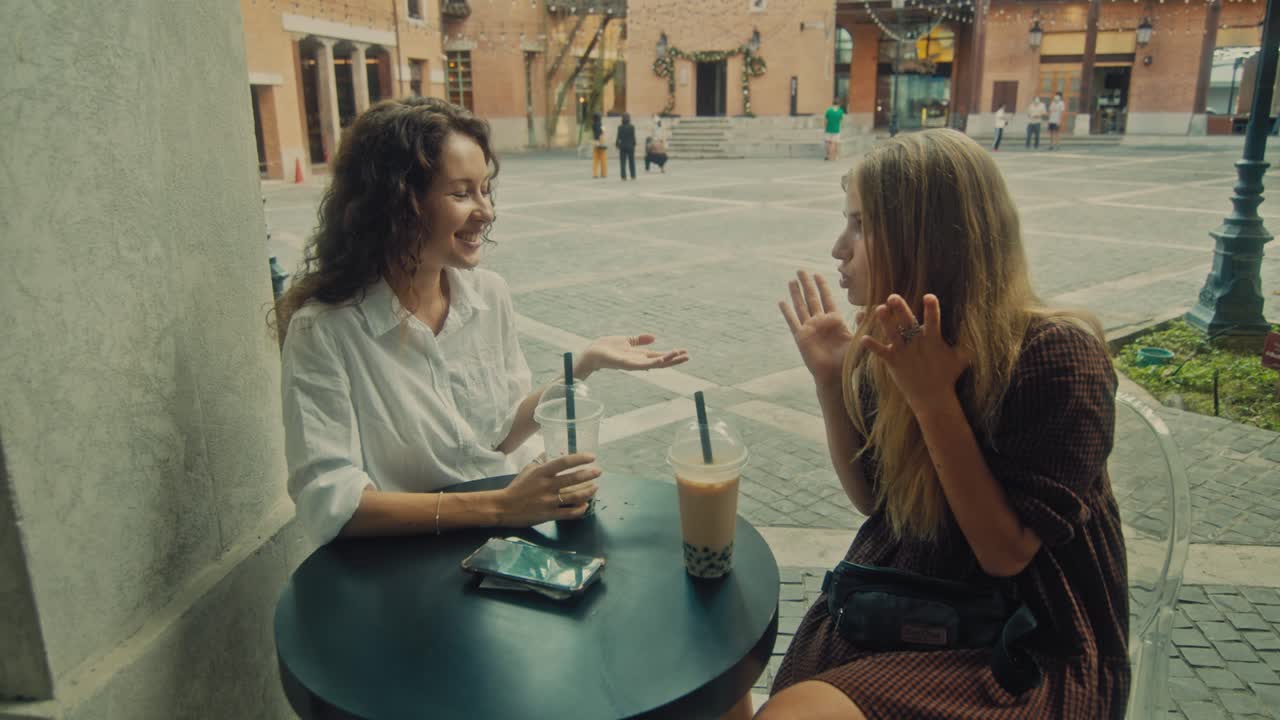 Two Women Enjoying Bubble Tea in a City Square