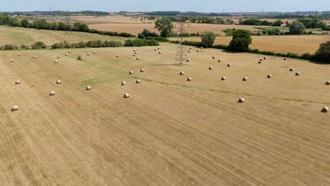 aerial drone footage of hay bales in farmland during harvest season in england on a sunny day