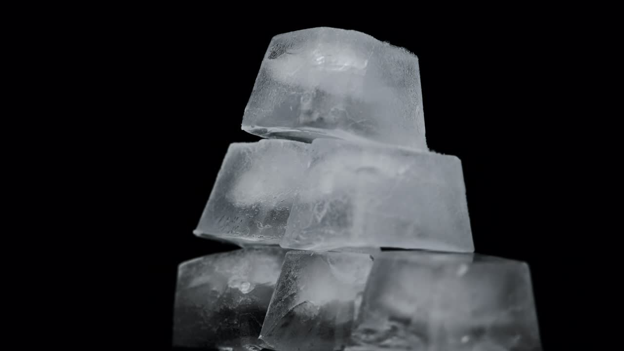 사각형 얼음 큐브가 검은 바탕에 회전하고 있습니다.