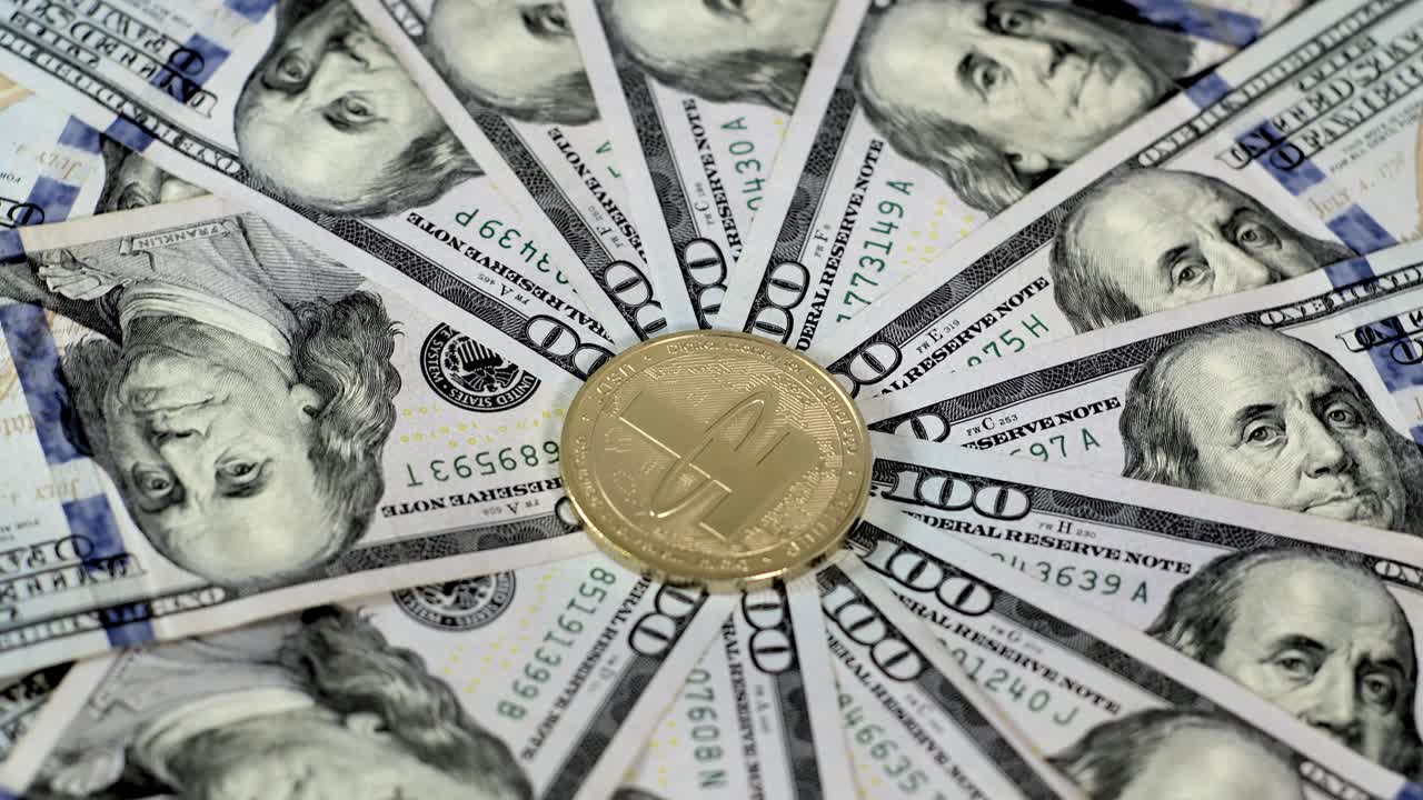 Money neatly arranged in radial pattern with shiny gold tangible USDT Tether coin at center of hundred dollar USD bills