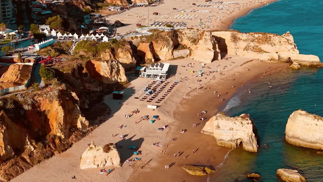 Besøgende slapper af på stranden i Portugal på en solskinsdag ved havet