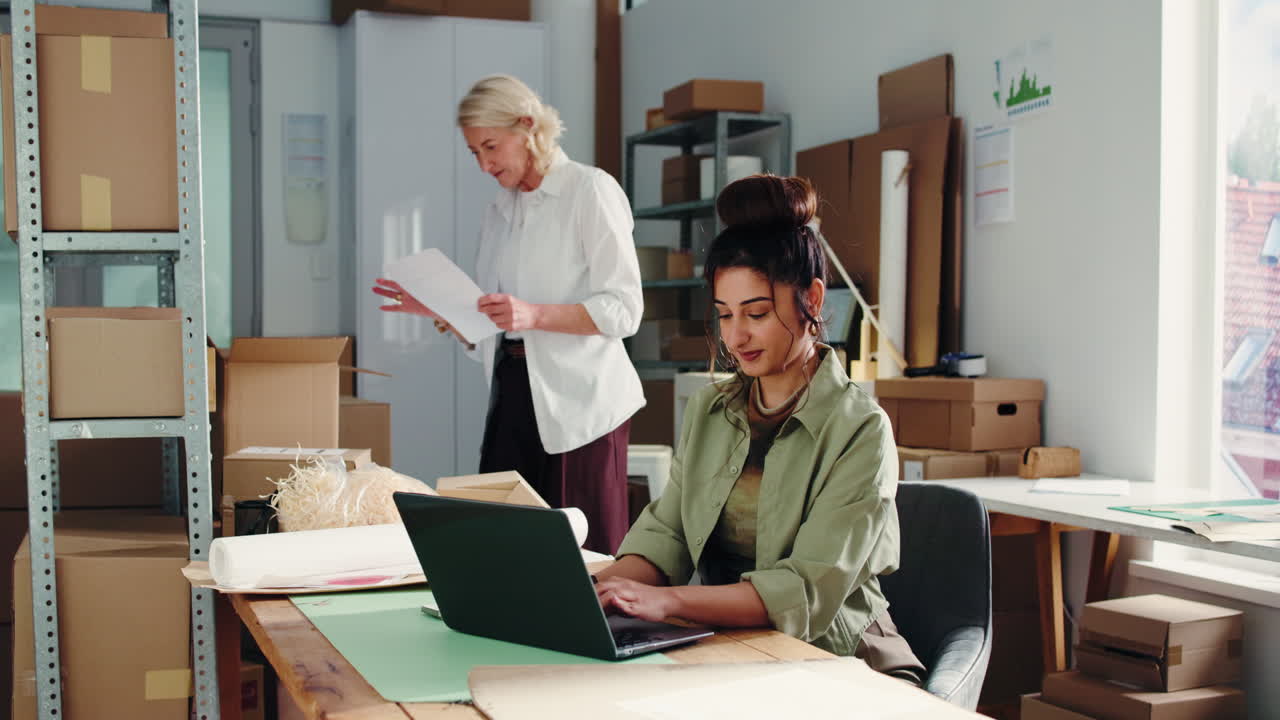 Due donne che lavorano al laptop e sui documenti in un ufficio di piccola impresa