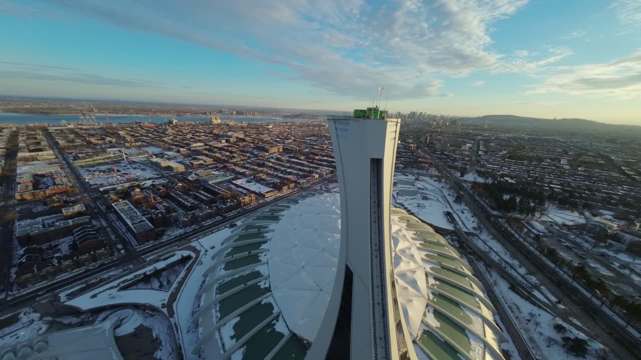 FPV drone captures panoramic winter views of Montreal Olympic Stadium under sunset light with snow cover