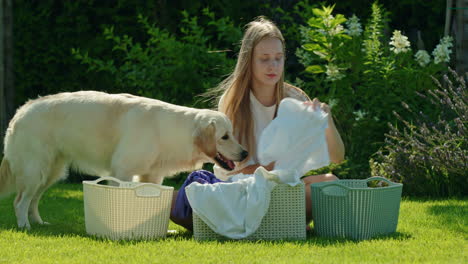 mujer joven lavando la ropa al aire libre con un perro