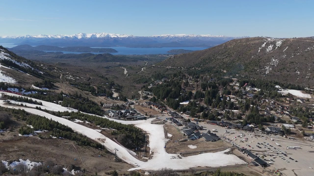 Ilmakuva Cerro Catedralista Patagoniassa, Argentiinassa, lumihuippuisine vuorineen, mutkittelevine polkuineen, tiheine metsineen ja kaukaisine Nahuel Huapi -järvineen kirkkaan sinisen taivaan alla.