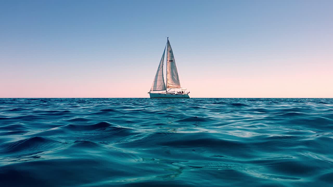 vista en ángulo bajo del nivel del mar de un pequeño yate navegando en mar abierto y tranquilo al atardecer